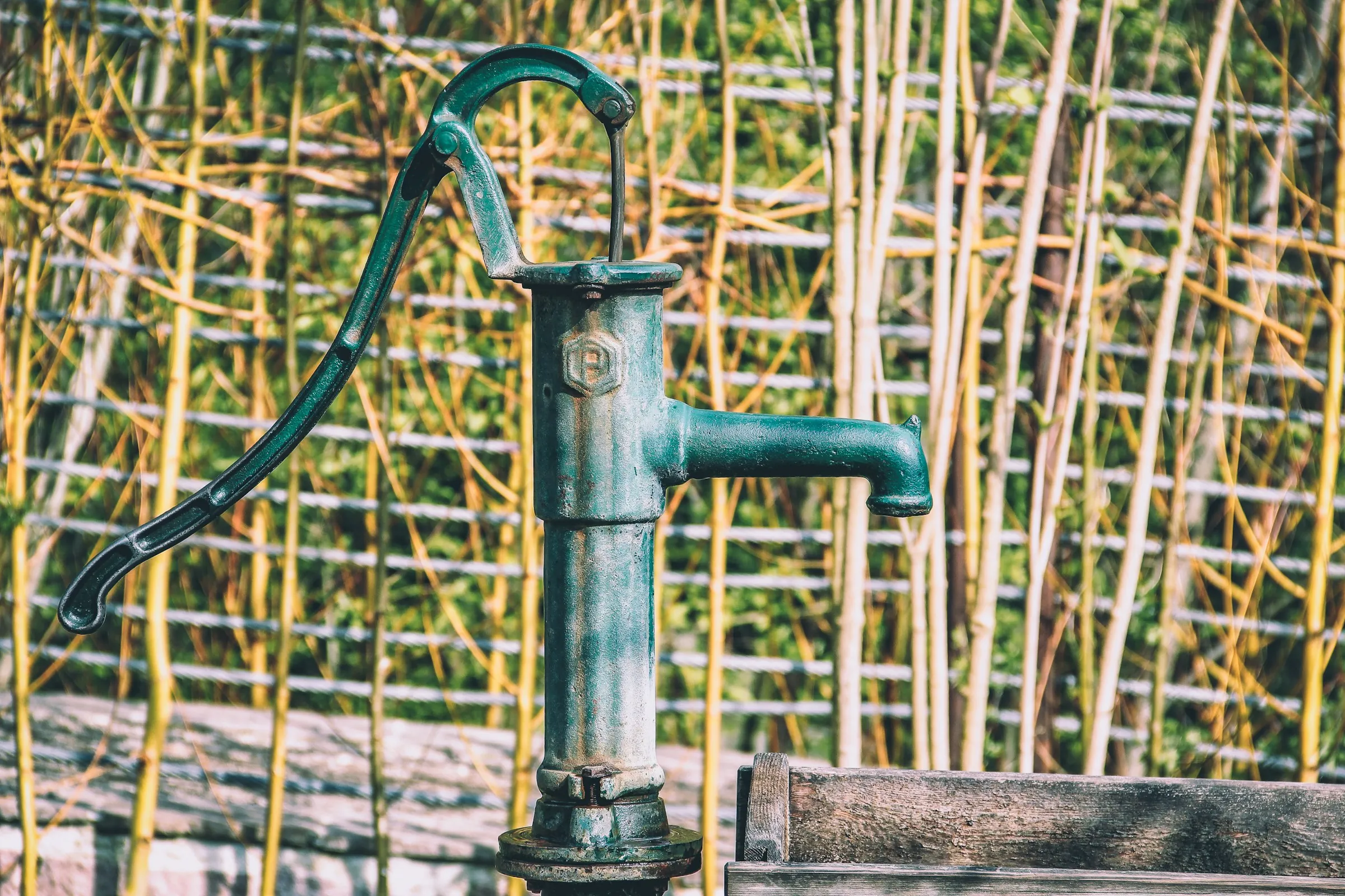 A green hand-operated water pump