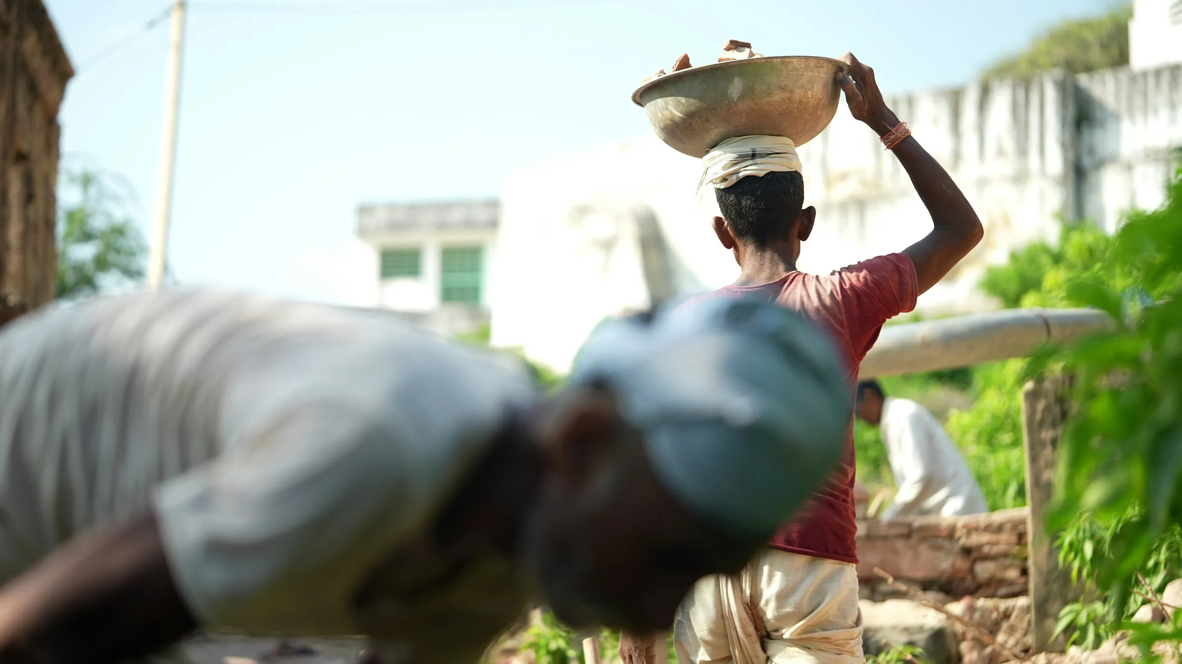 A woman carrying a bowl past a building site